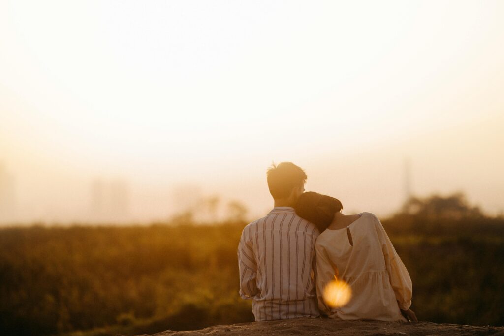 a couple with their backs turned towards the camera watching a sunset and leaning into each other shows that infusing emotion into design is a good way to conduct website design for social change
